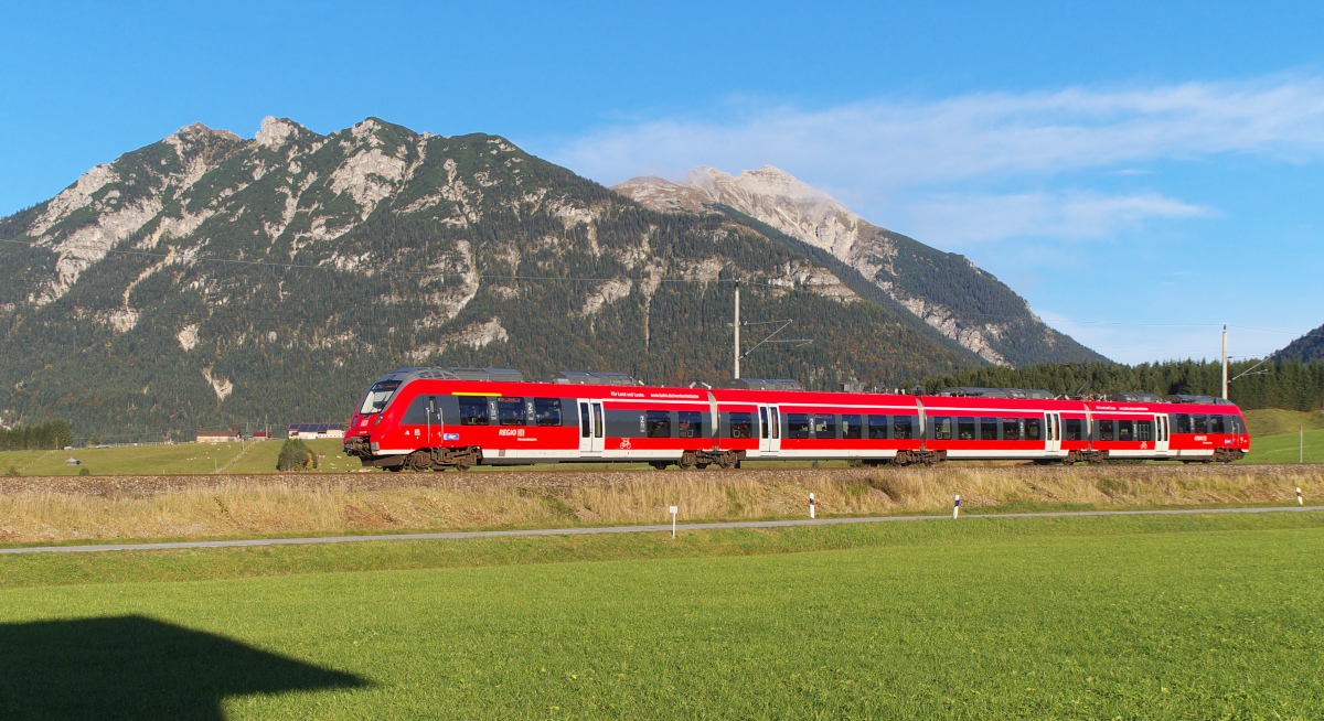 Ankommen, Koffer in die Ferienwohnung und sofort an die Strecke. Besonderen Spaß macht dies erstens, wenn die Wohnung nur 100 Meter von der Mittenwaldbahn entfernt liegt und zweitens, wenn  Kaiserwetter  am Karwendel (im Hintergrund die Soierngruppe) angesagt ist. Ein Hamster (BR 2 442 Österreich tauglich) kommt im abendlichen Sonnenlicht die Schmalenseehöhe hinunter. Der Triebwagen ist auf der Relation Innsbruck - Mittenwald (REX) - München (RB) unterwegs. Noch etwa eine Minute ist es bis Klais. Bahnstrecke 5504 München - Hbf. Mittenwald Grenze am 04.10.2015