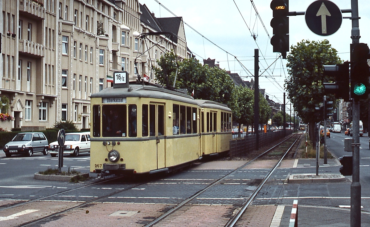 Anlässlich der Inbetriebnahme des U-Bahn-Tunnels zwischen Heinrich-Heine-Allee und Hauptbahnhof im August 1988 setzte die Rheinbahn zahlreiche Sonderzüge zwischen dem Düsseldorfer Hauptbahnhof und Oberkassel ein, darunter auch den Niederflurwagen 267, der hier als Linie 16/E auf der Luegallee unterwegs ist. Die Linie 16 verkehrte jahrzehntelang von Düsseldorf nach Neuss.