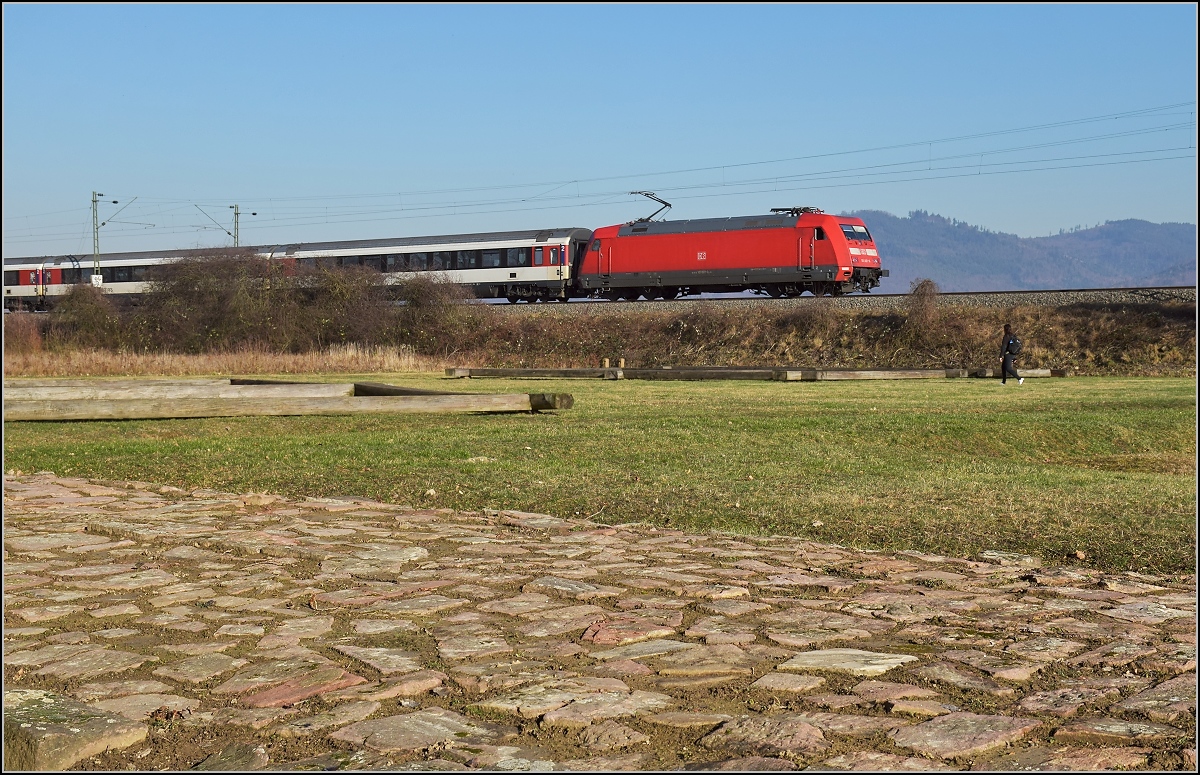 Antike und heute. Die badische Hauptbahn folgt in weiten Bereichen den alten Römerstraßen. Hier in Friesenheim wird ein Stück Römerstraße mit Raststätte an einer antiken Kreuzung gepflegt, netterweise direkt neben der Bahnstrecke. 101 115 mit einem EC auf Römerpfaden. Im Hintergrund ist noch der <I>Abnuba mons</I> zu sehen, zu deutsch Schwarzwald. Februar 2019.
