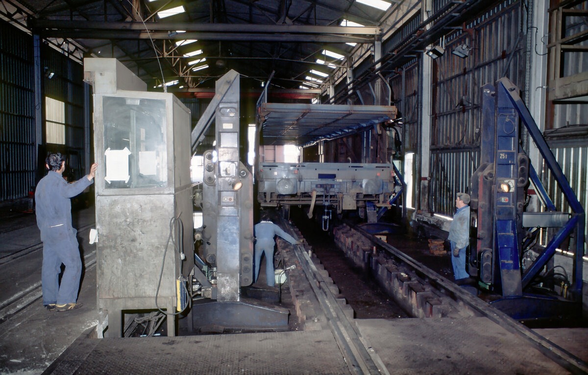 Arbeiter der spanischen Gesellschaft Transfesa sind in der Umspuranlage im französischen Grenzort Cerbère mit dem Anheben eines Güterwagens beschäftigt, um die Radsätze in die unterschiedliche Spurweite zwischen Frankreich und Spanien umzuwechseln (aufgenommen im Jahr 1983).