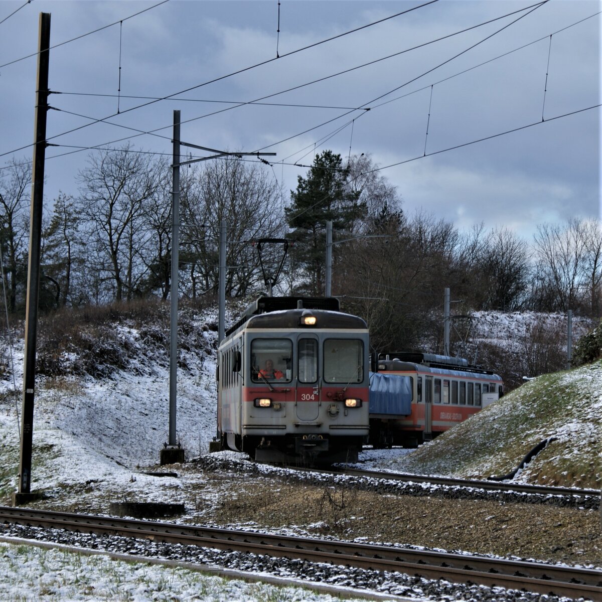 ASM BTI Aare Seeland mobil AG Biel-Täuffelen-Ins-Bahn: Be 4/4 304 + Fa 576 + Fa 571 + Fa 572 +  Be 4/4 302, Zug 8281 Finsterhennen-Sutz beim Verlassen der Grube  Uf der Höchi , Anschlussgleis Grube Finsterhennen, 9. Dezember 2021. An diesem Tag verkehrte das Zugpaar 8281/8286 zum letzten Mal. Zug 8281 wurde jeweilen vor der Mittagspause beladen, blieb über Mittag stehen und fuhr erst am Nachmittag nach Sutz. In der Grube waren Einrichtungen und Vorgehen gleich wie im Werk in Sutz: Die Ladung der gegen Absturz gesicherten Wagen wurde in eine Senke abgekippt und danach der Zug verschoben zum Beladen der Wagen durch einen Pneulader.