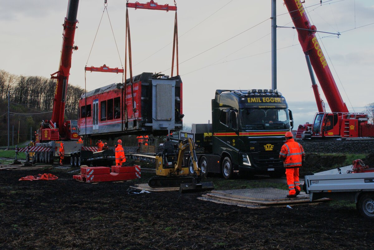 ASm BTI Aare Seeland mobil AG Biel-Täuffelen-Ins-Bahn: Verlad der Teile 506.1 und 506.0 (Traktionseinheit) des GTW 506, Lüscherzmoos, 1. April 2023 (gegen 19.30 Uhr). Der dritte Kran wurde zwischenzeitlich abgebaut und weggefahren. Der Strassentransporter kann unter die schwebende Last zurückschieben. 