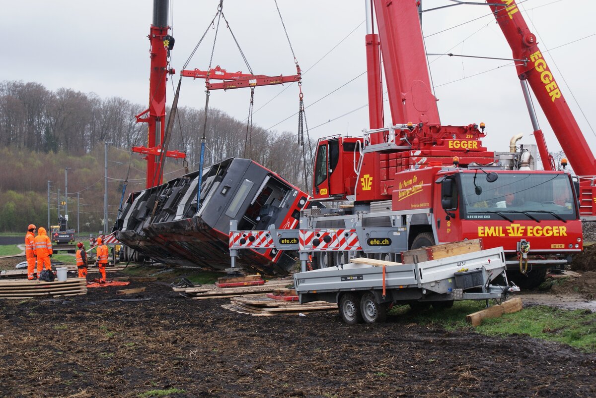 ASm BTI Aare Seeland mobil AG Biel-Täuffelen-Ins-Bahn: Aufrichten des GTW 506, Lüscherzmoos, 1. April 2023 (gegen 15 Uhr Sommerzeit). Zug 7099 Ins-Biel (ein  Langzug  GTW + GTW) verunfallte am Vortag um 16.30 Uhr. Der führende GTW 506 entgleiste und stürzte vom Bahndamm. Der zweite GTW kam im Gleis zu stehen ohne zu entgleisen. Drei Personen wurden verletzt. Sie konnten das Spital innert 24 Stunden wieder verlassen. Ein ähnlicher Unfall ereignete sich gleichentags gegen 17 Uhr in Büren zum Hof (Strecke Solothurn-Bern des Regionalverkehrs Bern-Solothurn). In beiden Fällen gilt als wahrscheinliche Unfallursache Sturmeinwirkung mit Böen in Orkanstärke. Die Bildfolge zeigt die Arbeit der Schwergutspezialisten:  Call the big hook  (ein amerikanischer Buchtitel) wäre auch hier passend. Beim Betrachten der Bilder soll nicht vergessen gehen, dass bei der Bewältigung solcher Ereignisse weit mehr Organisationen mit Mitarbeitern beteiligt sind.    
