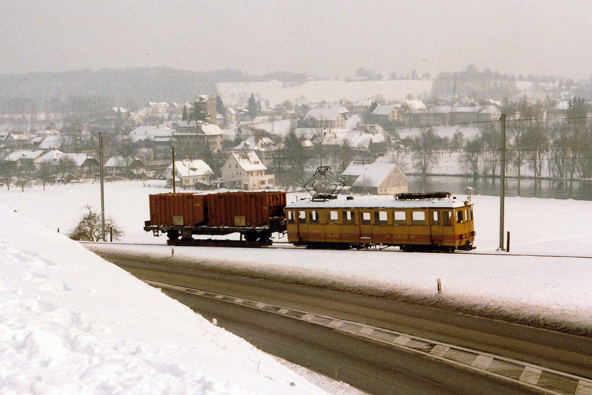ASm/OJB: Kehrichtzug Langenthal-Niederbipp mit De 4/4 122 ex LMB CFe 4/4 Nr 6 (1917) am Klebenstutz ob Aarwangen im Dezember 1985. Damals wurde der Kehricht noch von der Verladestation Langenthal mit Normalbahngüterwagen auf Schmalspur-Rollschemel zum SBB-Bahnhof Niederbipp transportiert, wo die Kehrichtwagen von einem SBB-Güterzug übernommen wurden, der sie nach Solothurn-HB brachte. Heute werden die Kehrichtwagen nur noch auf einem kurzen Schmalspur-Streckenabschnitt auf Rollböcken von der KEBAG-Verladestation zur ASm-Rollbockanlage Langenthal transportiert. Im September 1992 wurde der De 4/4 122 abgebrochen. Foto: Walter Ruetsch 