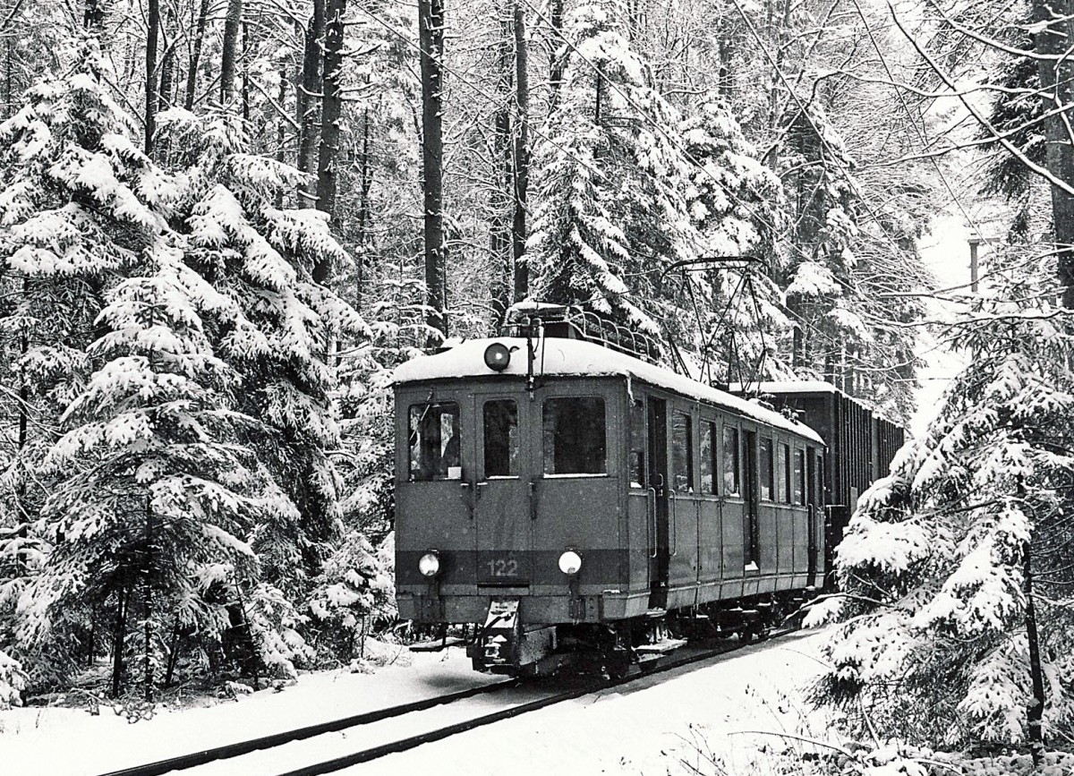 ASm/OJB: Kehrichtzug Langenthal-Niederbipp mit De 4/4 122 ex LMB CFe 4/4 Nr 6 (1917) im Hardwald im Dezember 1985. Damals wurde der Kehricht noch von der Verladestation Langenthal mit Normalbahngüterwagen auf Schmalspur-Rollschemel zum SBB-Bahnhof Niederbipp transportiert, wo die Kehrichtwagen von einem SBB-Güterzug übernommen wurden, der sie nach Solothurn-HB brachte. Heute werden die Kehrichtwagen nur noch auf einem kurzen Schmalspur-Streckenabschnitt auf Rollböcken von der KEBAG-Verladestation zur ASm-Rollbockanlage Langenthal transportiert. Im September 1992 wurde der De 4/4 122 abgebrochen. Foto: Walter Ruetsch