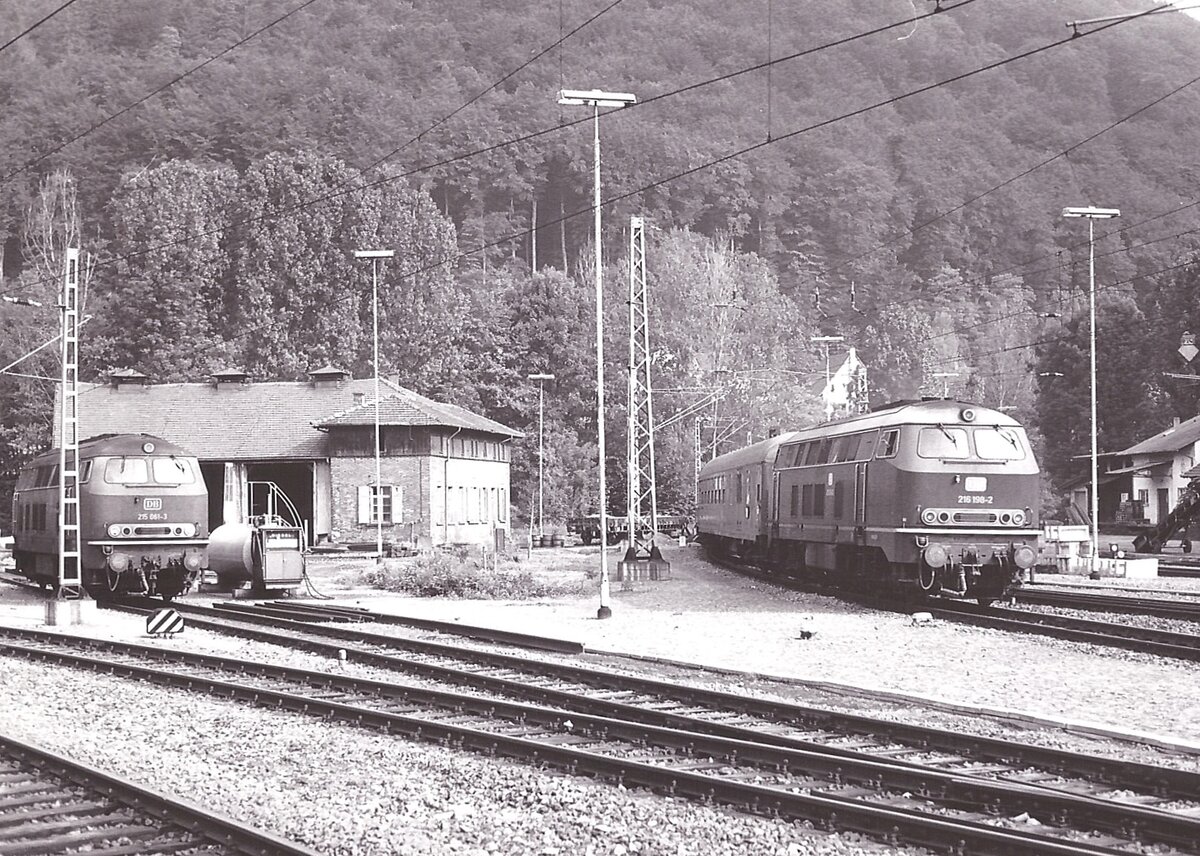 Auch das ist ein besonderes Bild von Rudolf Pavel.
Das Bild zeigt die Einfahrt eines Heckeneilzuges von der Odenwaldbahn der von der 216 198 aus Frankfurt Hbf kommend nach Stuttgart Hbf gezogen wurde in Eberbach. Es ist auch das ehemalige BW Eberbach zusehen, wo die 215 061 wartet um Kurswagen des Heckeneilzugs nach Heidelberg zu übernehmen. Die Aufnahme ist gegen Ende der 1970ger Jahre aufgenommen, leider hat er kein genaues Aufnahmedatum mehr.
P.S. Heute ist das ehemalige BW ein Parkplatz für Pendler.