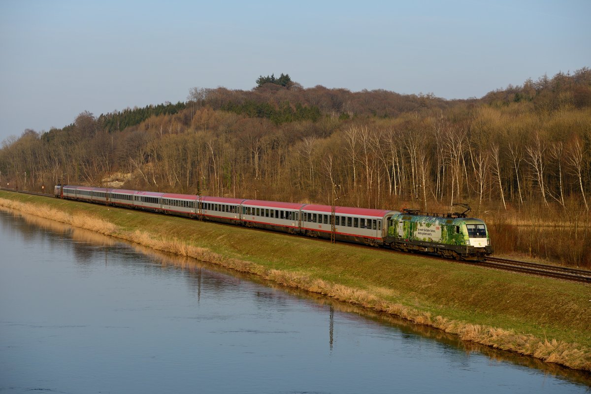 Auch hier wurde noch eine seitlichere Aufnahme mit weniger Brennweite angefertigt: Der stark verspätete EC 112 am Donauufer bei Günzburg, in  Sandwich-Bespannung  mit den Werbe-Tauri 1016.023 und 1116.153 (09. April 2015).