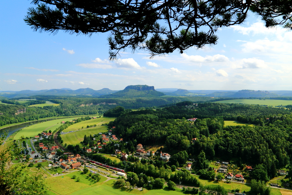 Auch dieser idyllische Blick bietet sich vom Bastei-Felsen in der Sächsischen Schweiz. Vor dem Hintergrund von Lilienstein und Königstein macht gerade ein S-Bahnzug aus Dresden im Örtchen Kurort Rathen Station. Die Aufnahme entstand am 16.06.2017.