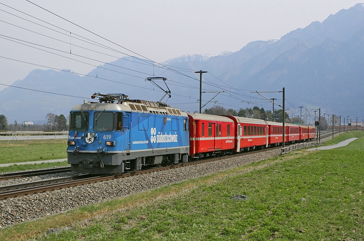 Auf dem Dreischienengleis von Chur nach Domat/Ems ist die Ge 4/4 II 619 am 29.03.2022 bei Felsberg mit einem Zug nach Disentis unterwegs