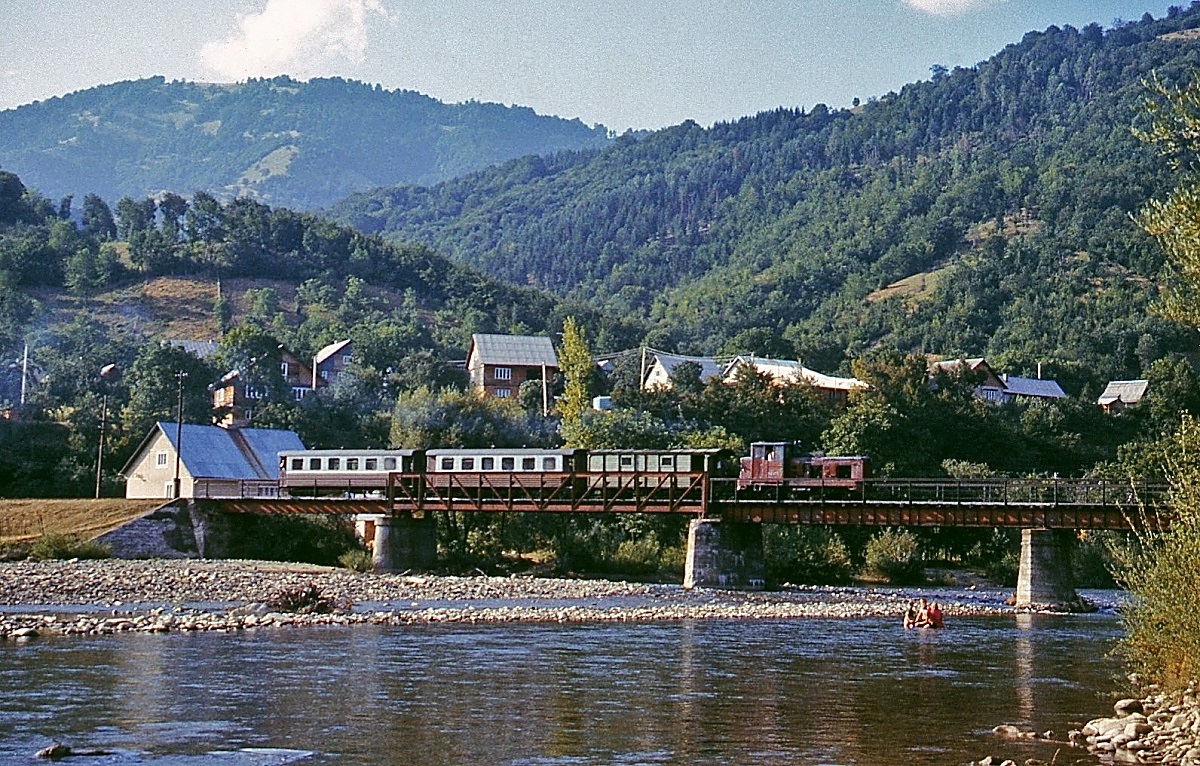 Auf dem Weg nach Ust-Tschorna in den ukrainischen Waldkarpaten überquert die Tu4 2075 der Waldbahn Tereswatal am 01.08.1994 die Tereswa. Diese Bahn führte von Tereswa unweit der ukrainisch-rumänischen Grenze entlang des gleichnamigen Flusses bis in das rd. 80 km entfernte Komarne. Mit Seitenlinien hatte das Waldbahnnetz zu seinen Glanzzeiten eine Länge von ca. 250 km. Leider wurde der Betrieb nach einem schweren Hochwasser im November 1998 eingestellt.