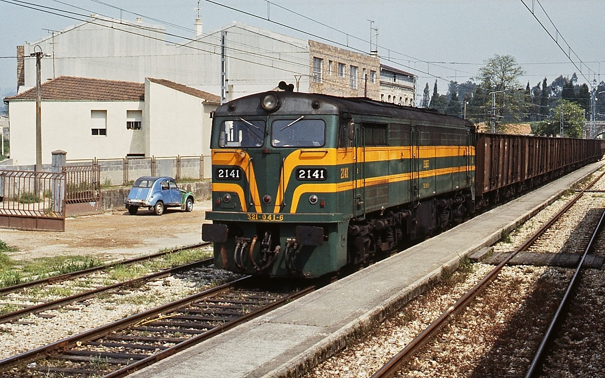 Auf einem Bahnhof an der Strecke von Santiago de Compostela nach La Coruna wartet die 321-041-6 eine Zugkreuzung ab. Die Loks gehören zum Typ DL500S von ALCo/USA, die auch die ersten 8 Loks herstellte. Die restlichen 68 Maschinen lieferten spanische Lokfabriken zwischen 1964 und 1967. 