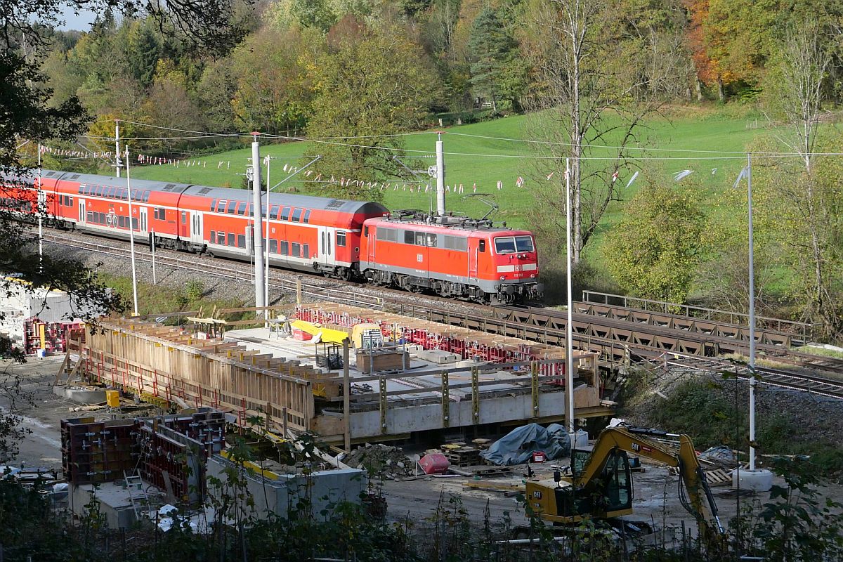 Auf der Fahrt von Lindau-Reutin nach Stuttgart schiebt 111 012 die Wagen des RE 5 / 4222 am 28.10.2022 im Schussentobel bei Kilometer 162.0 an einer Brckenbaustelle vorbei. Ab Ende November wird hier der Zug die Schussen nicht mehr auf einer genieteten Stahlfachwerkbrcke sondern auf einer WiB-Brcke (Walztrger-in-Beton-Brcke) berqueren.