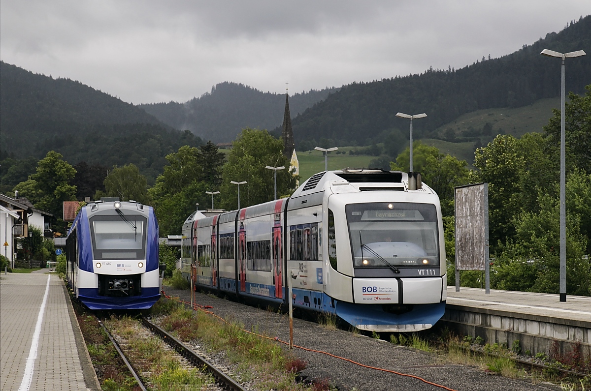 Auf ihrer Website verkündet die Bayerischen Regionalbahn: 
 Was ändert sich im Oberland-Netz (ehemals BOB)? Zum einen änderte sich seit Juni der Name von BOB auf BRB. Zum anderen werden nach und nach die alten BOB-Züge durch neue hochmoderne Triebwagen ersetzt. Am 26.7. wird der Flottenaustausch abgeschlossen sein. Insgesamt werden 31 Fahrzeuge des Typs Coradia Lint 54 des Herstellers Alstom im Rahmen eines Flottentausches sukzessive zum Einsatz kommen. 
Angesichts der Tatsache, dass ich zwischen dem 15. und 22.07.2020 auf dem Bayrischzeller Ast bis auf eine Ausnahme lediglich Integral angetroffen habe, klingt das sehr ehrgeizig. Diese Ausnahme war der VT 487, der am 16.07.2020 im Bahnhof Schliersee stand, daneben verläßt VT 111 den Bahnhof in Richtung Bayrischzell.
