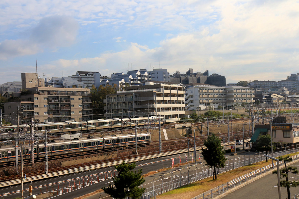Auf der S-Bahnstrecke von Ôsaka aus nach Westen, der Inlandsee entlang: Am selben Ort wie das vorige Bild; jetzt fahren ein JR-Zug mit Halt an allen Stationen (Serie 207) und ein JR- Neuer Eilzug  (= nicht zuschlagspflichtiger Expresszug) (Serie 223, 3-türig, mit bequemen Sesseln) mit Halt nur an wichtigen Stationen ein. Asagiri, 6.November 2018  SANYÔ HAUPTLINIE 