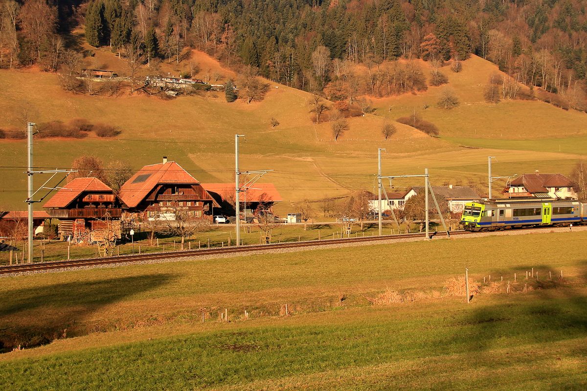 Auf der Suche nach Kombinationsmöglichkeiten von Bahnbild und Emmentaler Bauernhaus. Hier in Zäziwil kommt die Bahn an einem schönen Ensemble von Haus+Stall+Scheune (rechts) und kleinem Stöckli (links davon) vorbei. BLS NPZ-Triebwagen 737 fährt gerade ins Bild ein. 15.Dezember 2016. 
