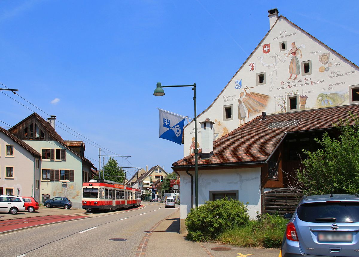 Auf der Waldenburgerbahn - die Fahne macht's deutlich: Wir sind in der Gemeinde Oberdorf. Triebwagen 16 beim Haus von 1658 mit allerlei denkwürdigen Texten daran. 22.Juni 2017