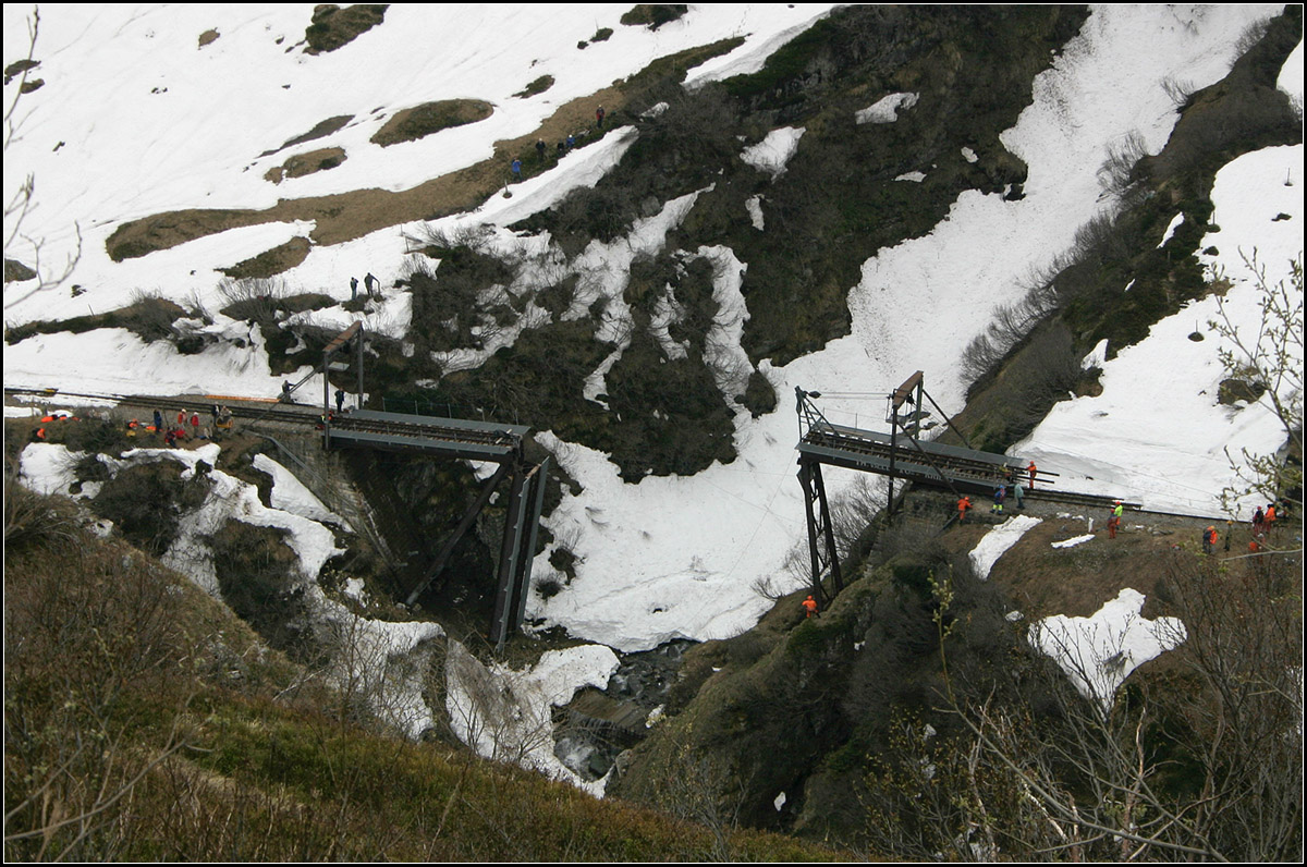Aufbau der Sommerbrücke -

Steffenbachbrücke an der Furka-Dampfbahn. Über den Winter wird diese Brücke zusammengeklappt. Die beiden seitlichen Fahrbahnteile werden rechts und links über die Strecke gezogen, die Stützen legen sich dabei an die Widerlager an. Das mittlere Brückenteil hängt nach unten auf der linken Stütze. 

15.05.2008 (M)