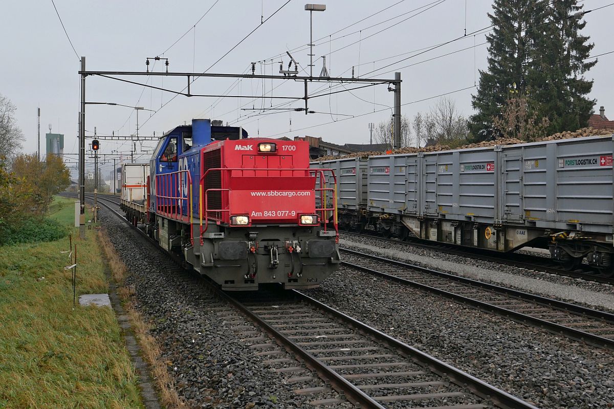 Aus Richtung Frauenfeld kommend durchfährt Am 843 077-9 mit einem Container eines Bahninfrakstrukturunternehmens auf einem Flachwagen Bürglen (TG) in Richtung Sulgen. Aufnahmestandort am Ende des Bahnsteigs am 10.11.2021.
