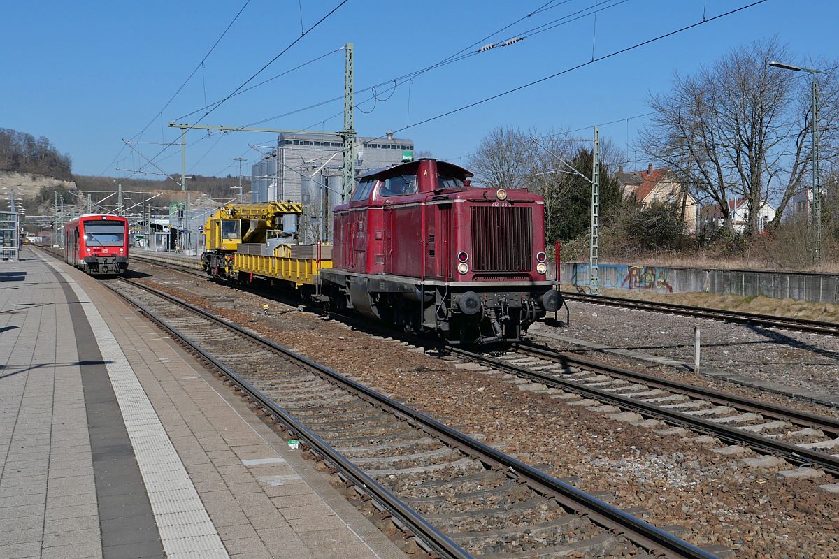 Aus Richtung Ulm kommend zieht 212 133-3 den Kirow Eisenbahndrehkran 901 der DB Bahnbau Gruppe mit Schutzwagen durch den Bahnhof von Biberach (Riß) nach Aulendorf (28.02.2022)