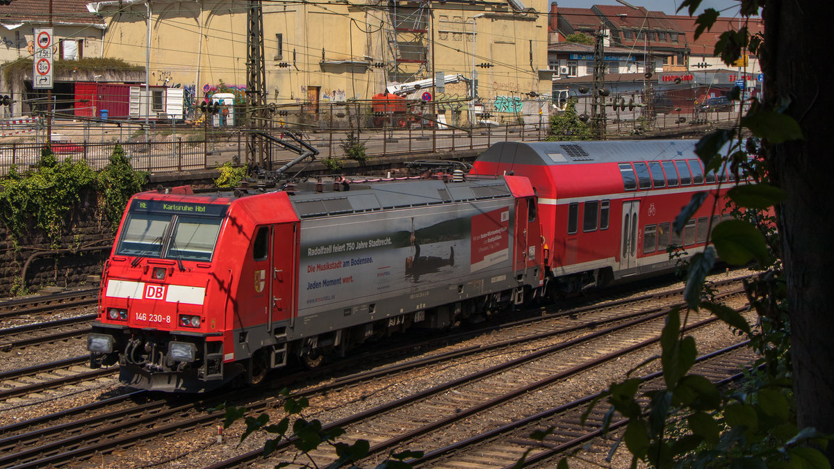 Ausfahrt Bahnhof Offenburg gen Karlsruhe am 25. Juli 2018. Die Werbelok 146 230-8 mit dem RE fährt an der Linse des Fotografen vorbei, der sich gerade unter den Bäumen etwas Schatten gönnt. 