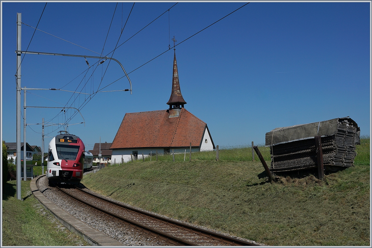 Ausgangs von Vaulruz, bei der Kapelle ist dieser TPF RABe 527 195 als RE in Richtung Bern unterwegs. 

19. Mai 2020