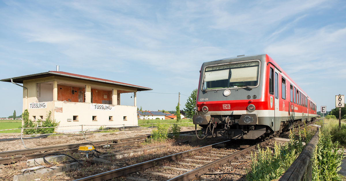 Ausgedient
hat das alte Stellwerk am Nordkopf des Bahnhofs Tüssling. Im Zuge des zweigleisigen Ausbaus der Strecke Mühldorf - Tüssling wird das neue Streckengleis in Höhe des Stellwerks in den Bahnhof eingefädelt werden. 628 426 fährt am 10.06.2016 auf seinem Weg von Mühldorf nach Burghausen in den Bahnhof Tüssling ein (Nachschuss).