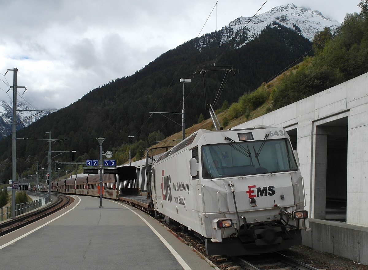 Autoverlad Vereina - Damit Lkw, deren Maße das Verladeprofil der Autotransportwagen mit Schutzdach überschreiten, mitgenommen werden können, muss Ge 4/4 III 643 mit den überdachten Wagen soweit vorfahren, dass der Lkw an der Verladerampe auf den hier am Zugende nicht überdachten Auffahrwagen fahren und mitgenommen werden kann. Station Sagliains, 24.09.2015.
