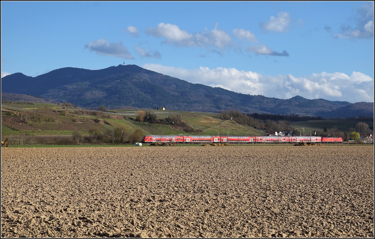 Bahn im Markgräfler Land. Allzulange wird es diesen Blick nicht geben, denn die Ära der roten Züge neigt sich in Südbaden dem Ende zu. Hier in voller Pracht vor dem Blauen mit 146 205. Hügelheim, März 2019. 