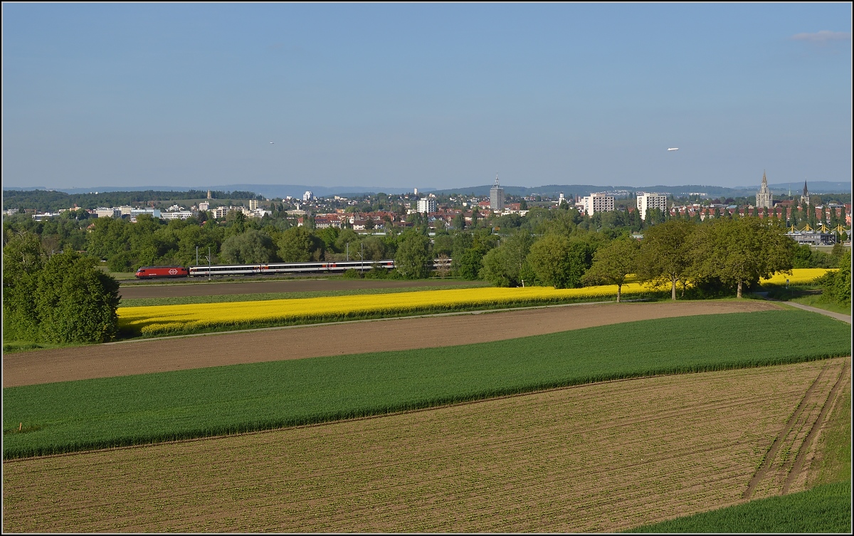 Bahn im Tägermoos - bei Sonnenschein. 

IR Konstanz-Biel. Im Hintergrund der Startort des IR. Mai 2014.