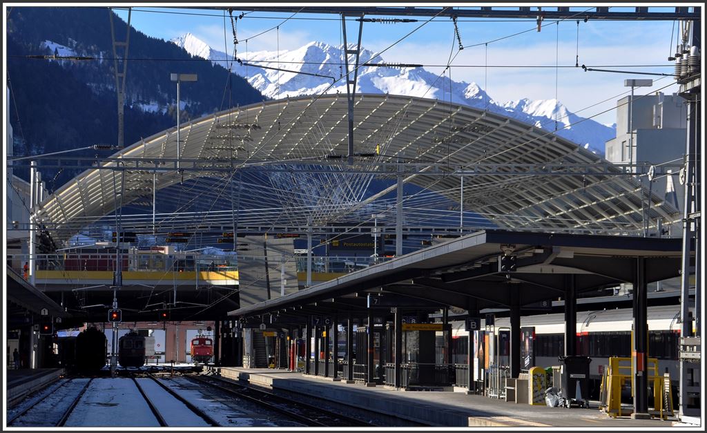 Bahnhof Chur mit Glasdach über dem Postautodeck und die Berge des Safientals mit Piz Fes. (11.02.2015)
