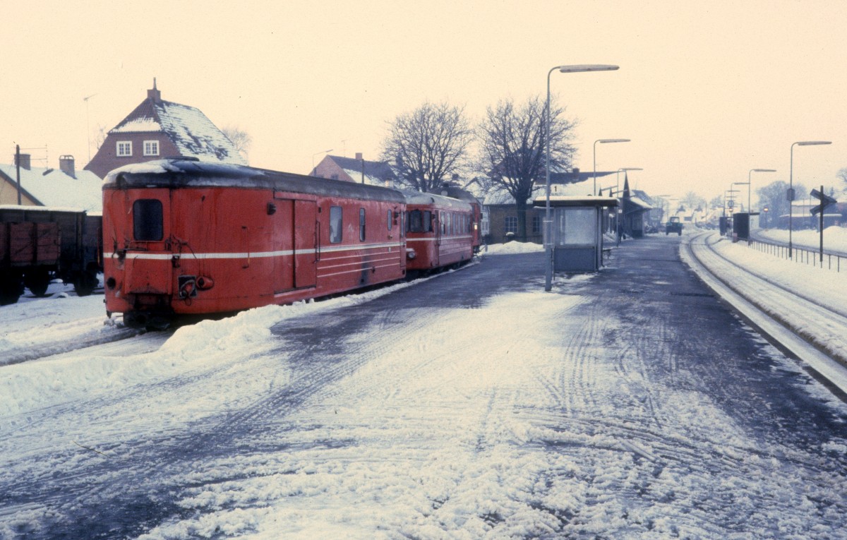 Bahnhof Tølløse am 28. Dezember 1981: Am HTJ-Bahnsteig steht ein Triebzug bestehend aus dem HTJ-Triebwagen S 44 (vorne) und dem OHJ-Postwagen D 246. - Der Triebzug war im Schnee stecken geblieben und wurde deshalb von einer Diesellok abgeholt. Auf dem Bild wartet der Zug auf die Weiterfahrt zur HTJ/OHJ-Werkstatt in Holbæk.
HTJ: Høng-Tølløse-Jernbane. Das Unternehmen bediente die Bahnstecke Tølløse - Høng - Slagelse.
OHJ: Odsherreds Jernbane. Dieses Unternehmen bediente die Bahnstrecke Holbæk - Nykøbing Sjælland.
Auf den beiden Strecken fahren heute Triebzüge des Unternehmens Regionstog. 