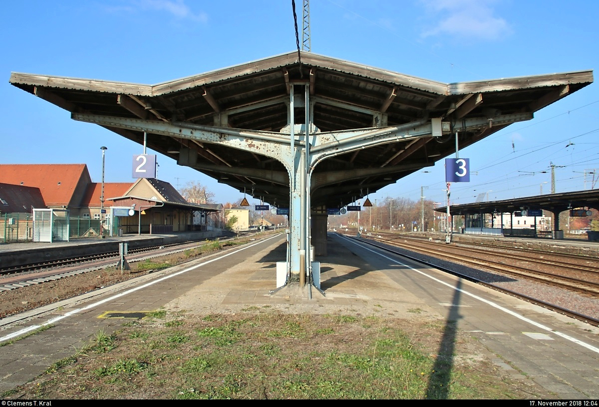 Bahnhofsumbau in Köthen: Eindrücke der historischen Anlagen in ihren letzten Monaten...
Blick auf das historische Bahnsteigdach auf Bahnsteig 2/3.
Hauptsächlich von Juni bis Dezember 2019 werden einige bahntechnische Anlagen in und rund um den Bahnhof erneuert. Ein elektronisches Stellwerk (ESTW) soll künftig die vorhandenen Stellwerke ersetzen. Im Zuge dessen folgen bis zum Ende der 2020er-Jahre weitere Instandsetzungen entlang der Bahnstrecke Magdeburg–Leipzig (KBS 340) zwischen Zöberitz und Köthen. Dann sollen auch Bahnsteige und Brücken unter Berücksichtigung des Denkmalschutzes ertüchtigt werden.
Diese Maßnahmen ziehen zunächst eine sechsmonatige Vollsperrung mit sich. Bereits ab dem 5.5.2019 ist die Ein- und Ausfahrt Richtung Bernburg gesperrt.
[17.11.2018 | 12:04 Uhr]