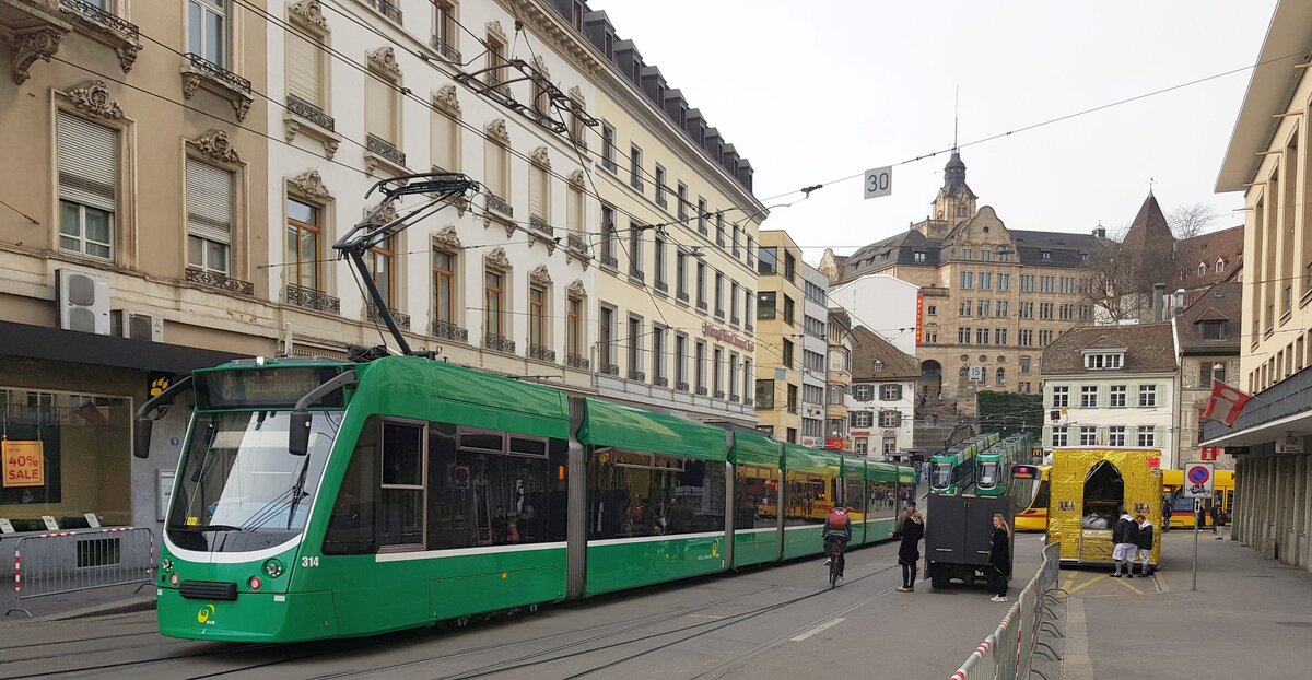 Basel BVB_Noch herrscht auf den Gleisen der normale Hochbetrieb, aber die Absperrgitter für den nachmittäglichen großen Umzug, den Cortège, stehen (ausschließlich) hier beim Theater schon. Drei grüne und ein gelber Zug beim Blick Richtung Barfüsserplatz.__02-2024