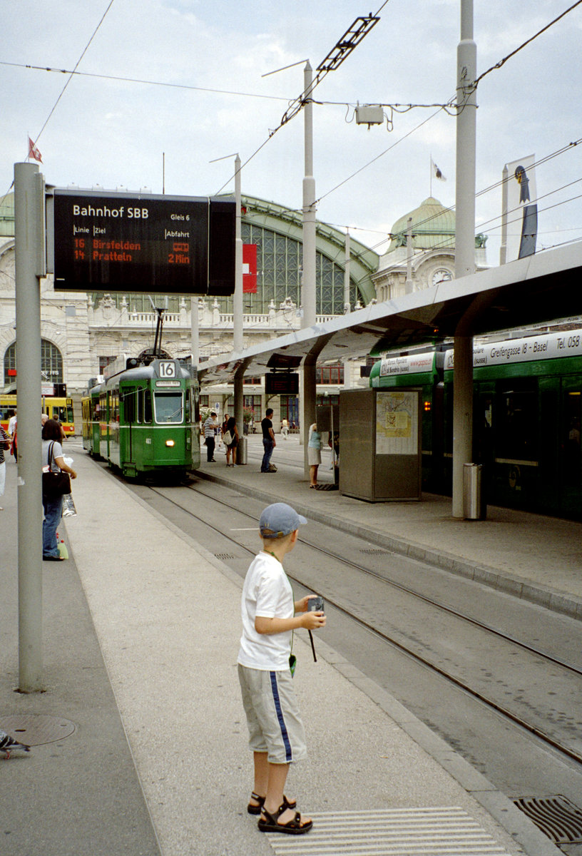Basel Tramhaltestelle Centralbahnplatz / Bahnhof SBB: Einige Fahrgäste, u.a. ein junger Bahnhfotograf (mein Sohn Stefan) warten die Ankunft der Tramlinie 16 ab. - Datum: 26. Juli 2006. - Scan eines Farbnegativs. Film: Kodak Gold 200-6. Kamera: Leica C2.