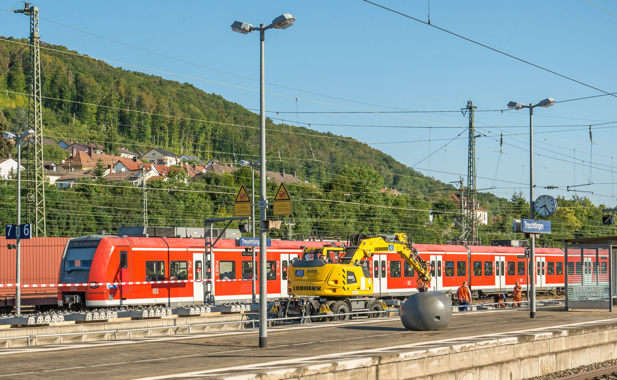 Bauarbeiten in Treuchtlingen am 9.8.22: 425 544 fuhr auf Gleis 7 nach Würzburg ab und im Nebengleis waren ein Zwei-Wege-Bagger und drei Arbeiter aktiv. Wodurch die Szene in den  vier Farben blau, grün, gelb und rot erstrahlte.