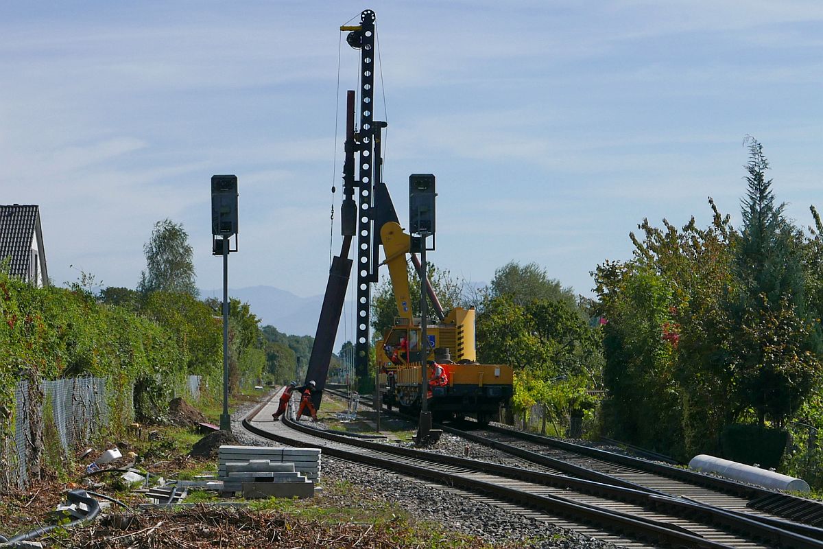 Bauarbeiten zur Elektrifizierung der Bodenseegrtelbahn, Streckenabschnitt Friedrichshafen - Lindau (|) - Zwei Arbeiter helfen tatkrftig, den Doppel-T-Trger, die Grndung fr einen Oberleitungsmasten aus Beton, in die richtige Position zu schieben, damit die selbstfahrende Ramme diesen in den Boden vom Bahnhof Eriskirch rammen kann (20.09.2019).