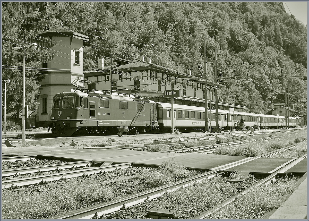Baubedingte Sperrung der Simplonstrecke zwischen Iselle und Domodossola: Die SBB Re 4/4 II 11161 wartet mit ihrem IR 3220 in Iselle auf die Abfahrt nach Brig. 
Der Zug besteht aus folgenden Reisezugwagen: A 50 85 18 35 028-1, B 5085 20 35 265-1, B 50 85 20 316-2 und dem BDt 50 85 82 33 923-2. 

Das Bild entstand, indem ich meinen kleinen Fotoapparat (Coolpix 7900) durch den Gitterzaun schob und dann abdrückte. 

19. August 2020
