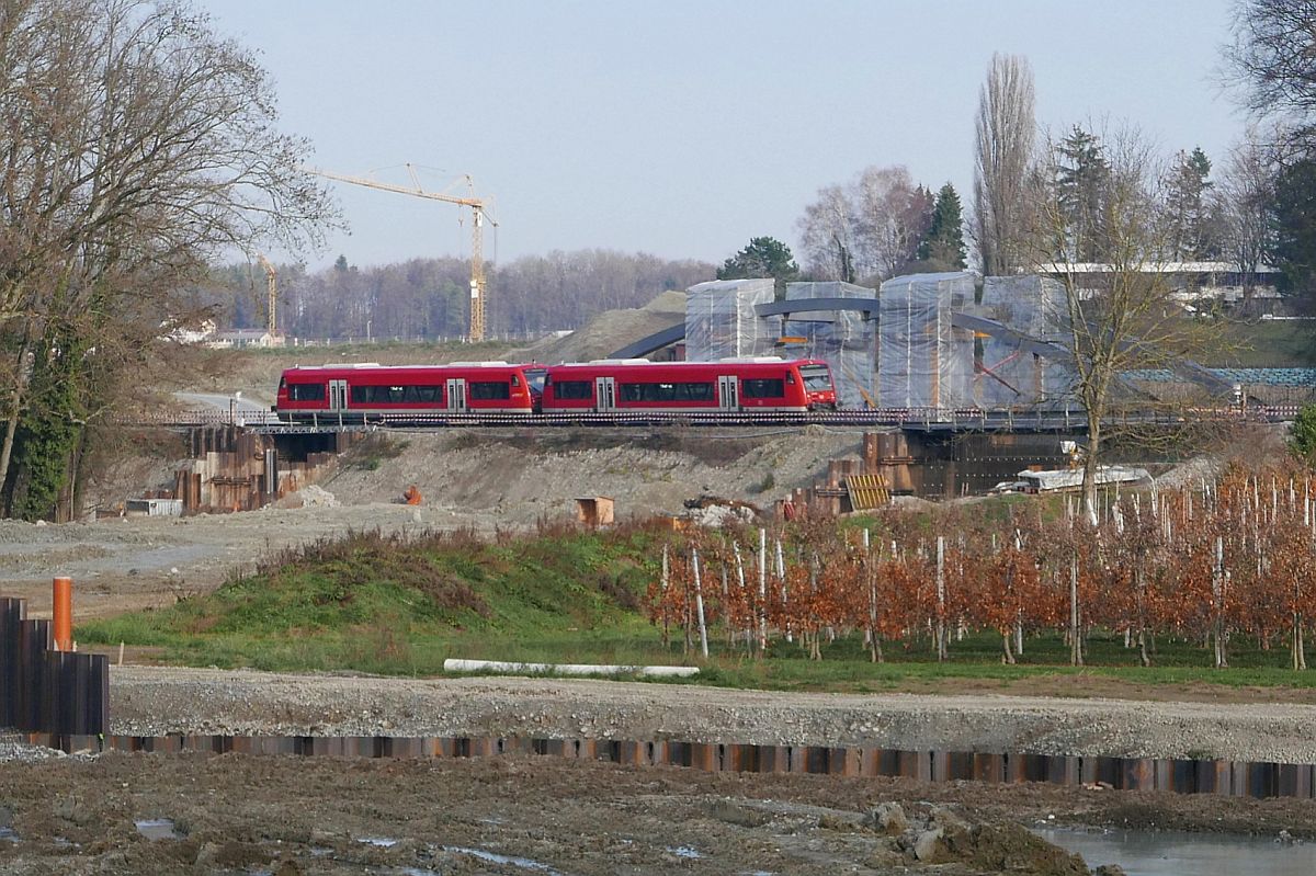 Baustelle Eisenbahnbrücke über die B31n (||) - Am 15.12.2018 ist bei Fischbach bereits die zukünftige Brücke teilweise zu erkennen, die neben der Bahnstrecke errichtet wird. Zwei Regio Shuttle fahren als RB 22772, Friedrichshafen - Radolfzell an der Baustelle vorbei.