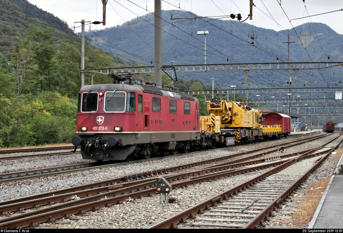 Bauzug mit Re 4/4 II 11273 (420 273-5) SBB durchfährt den Bahnhof Rivera-Bironico (CH) auf der Gotthardbahn am Monte Ceneri (600) Richtung Bellinzona (CH).
Hinter der Zuglok sind eingereiht:
- ein Kirow Gegenlastwagen der Gattung  Xas  (99 85 93 10 011-3 CH-SBBI),
- ein Brückenbaukran Kirow KRC 1200 (XTmaas 99 85 94 19 500-5 CH-SBBI) sowie
- ein Kran-Begleitwagen der Gattung  Xs  (40 85 95 47 712-1 CH-SBBI) der SBB Infrastruktur.
Aufgenommen von einem öffentlich zugänglichen Parkplatz.
[20.9.2019 | 12:01 Uhr]