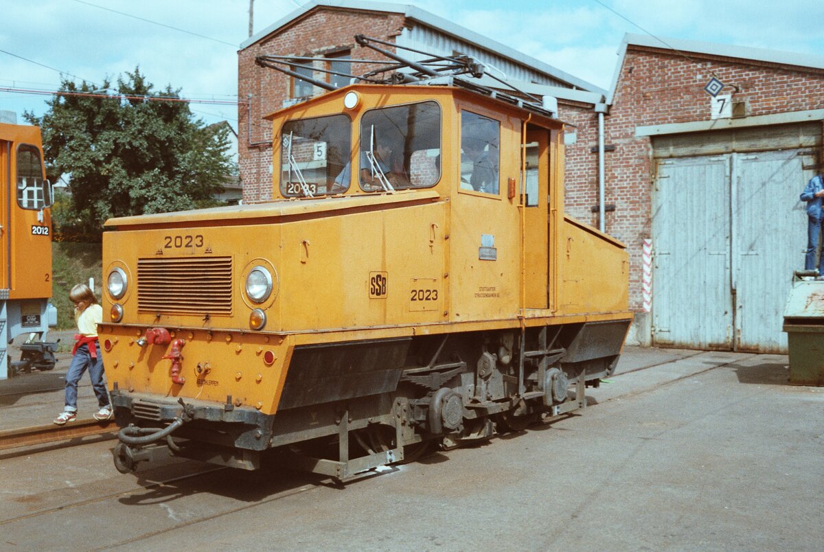 Bauzuglokomotive 2023 (SSB) vor dem früheren Wagenschuppen der Filderbahn in Möhringen. Die Lok war 1946 von der MF Esslingen und BBC als  Trümmerlok  gebaut worden. Sie ist in der Straßenbahnwelt Stuttgart erhalten. 
Datum: 04.09.1983 