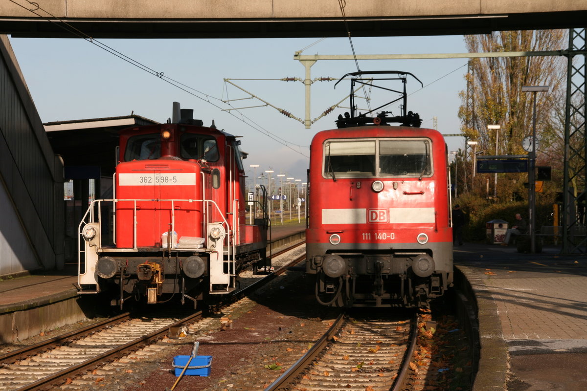 Begegnung im Hauptbahnhof Emden. Abgestellt sind BR 362 598 (V60) und BR 111 140. Gesehen am 04.11.2009 um 11:30 Uhr. Interessant ist, dass der blaue Eimer im Vordergrund auf vielen Aufnahmen im Bahnhof Emden zu sehen ist. ;-))