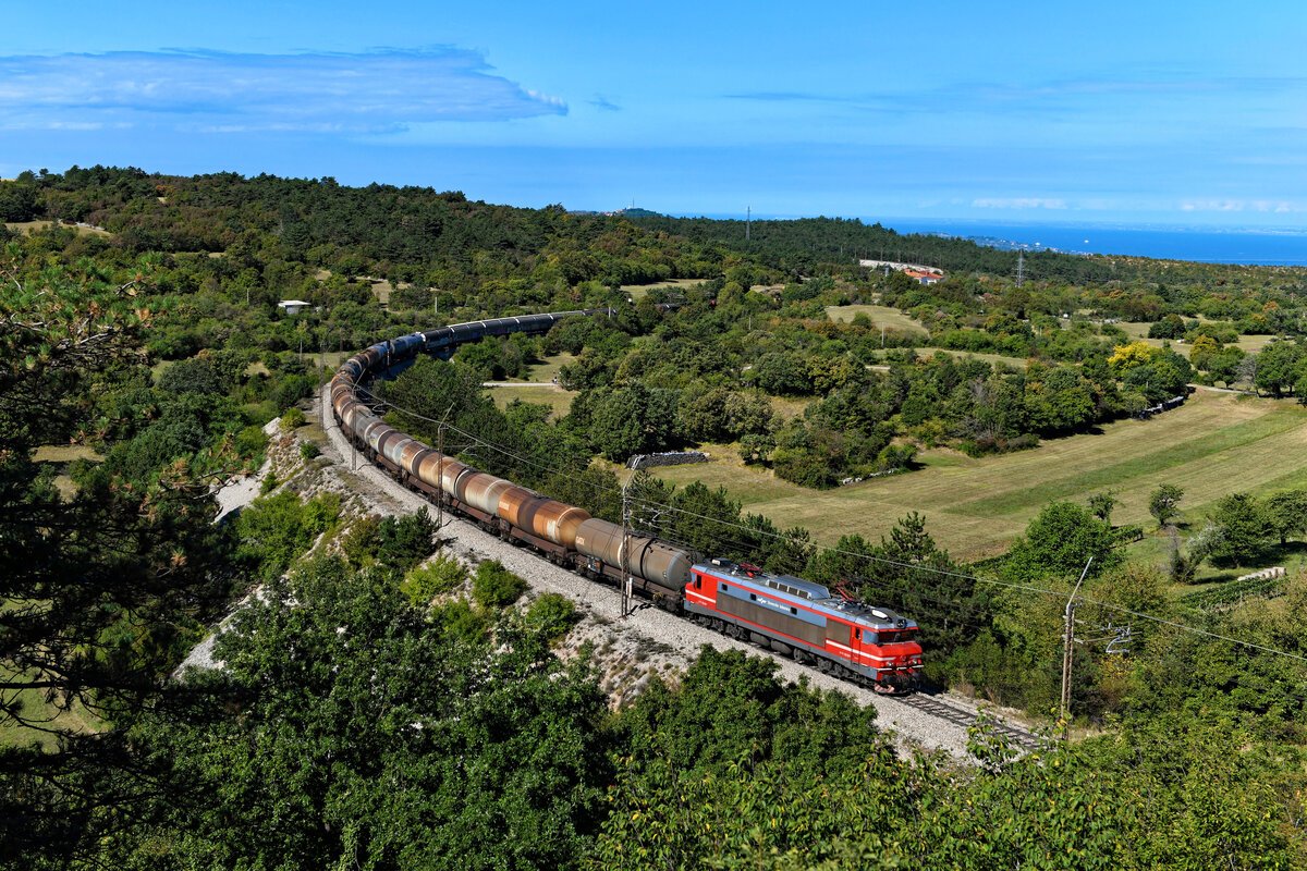 Bei Črnotiče ergibt sich dieser schöne Blick auf die sich durch die istrische Landschaft schlängelnde Bahnstrecke von Koper nach Prešnica. Im Hintergrund kann man die Adria und das italienische Festland erkennen. Kurz nur wird die Ruhe in dieser dünn besiedelten Gegend gestört, als sich die 363 038 mit einem gemischten Güterzug die Steigung hinauf kämpft, unterstützt von einer 541 am Zugschluss (18. September 2021).