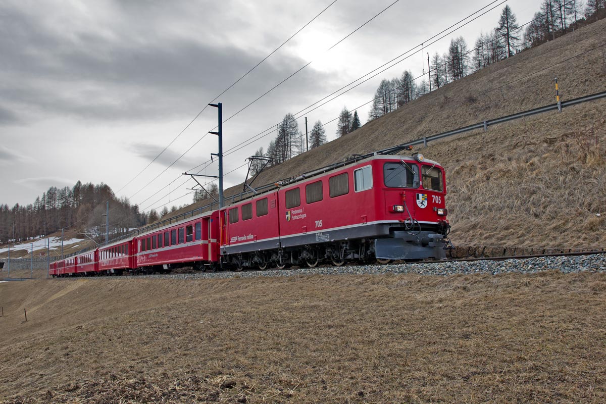 Bei Cinous-chel fährt die Ge 6/6 II 705  Pontresina  mit einem Re von Samedan nach Scuol vorüber.Bild vom 3.4.2016