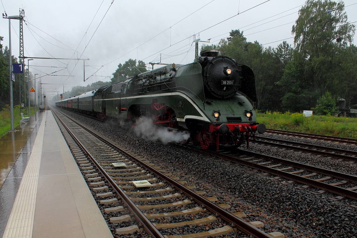 Bei Dauerregen fährt die 18 201 mit ihrem Sonderzug zur Hanse-Sail nach Rostock, hier bei der Durchfahrt am 12.08.2017 in Nassenheide.