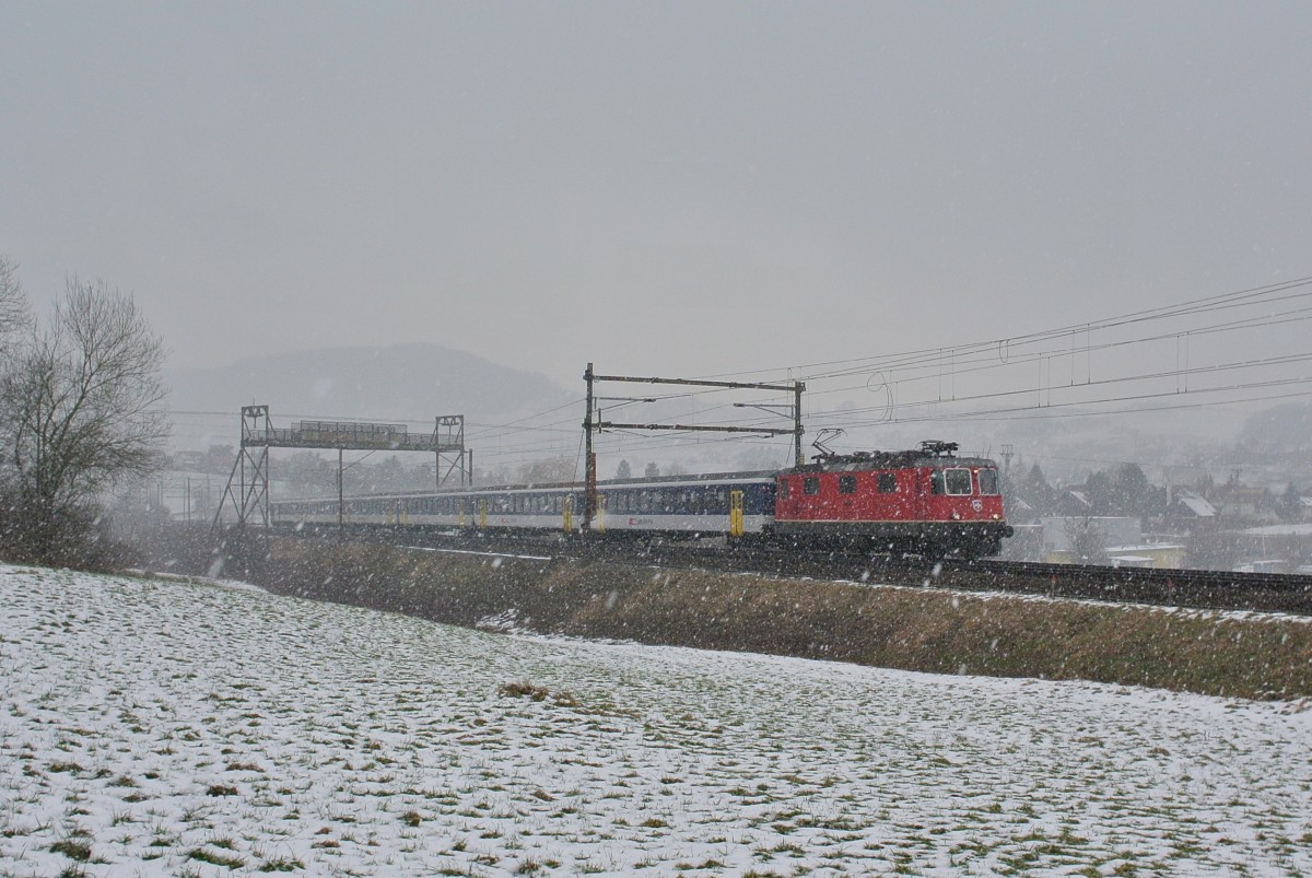 Bei dem unerwarteten Schneegestber kam auch noch ein unerwarteter Ersatzzug angefahren; Re 4/4 II 11208 mit einem S-Bahn Basel Einschaltpendel (4B EWI, AB EWII und BDt EWI 992-7) als Ersatz Flugzug IR 2078 oberhalb von Frick, 08.02.2015.