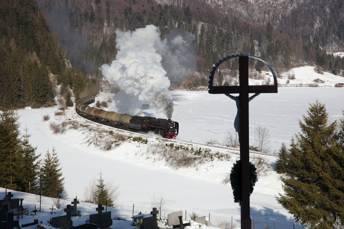 Bei Dobšinská+Maša fährt die 556 053 mit ihrem Kesselwagenzug über den Bahndamm - links und rechts davon der zugefrorene Stausee Palcmanská Maša. (09.02.2020)