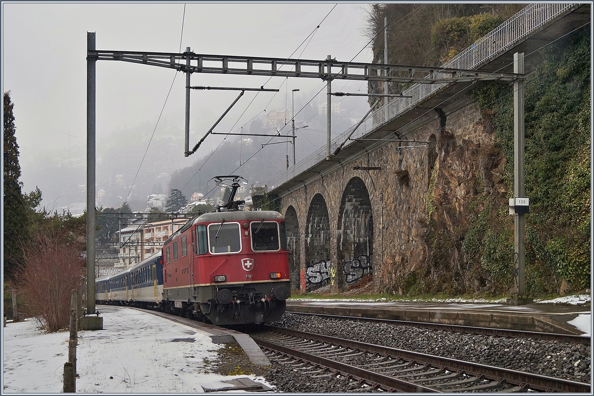 Bei eher ungemütlichem Wetter schiebt bei der Station Veytaux-Chillon die Re 4/4 II 11197 einen Dispo-Zug Richtung Lausanne. (die an der Spitze ziehende Re 4/4 II welche den überraschenden Zug ankündige, vermochte ich nicht mehr zu fotografieren) 
3. März 2018