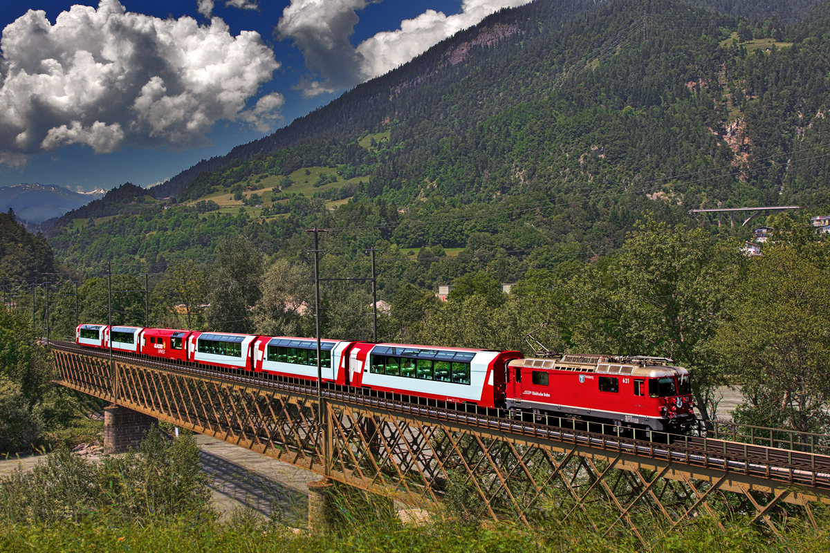 Bei einem zur Mittagszeit langsam aufziehenden Gewitter fährt die Ge 4/4 II 621  Felsberg  mit einem GEX über die Eisenbahnbrücke über den Rhein in Reichenau-Tamins.Bild vom 24.6.2016