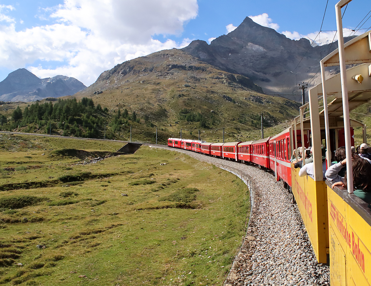 Bei einigen Regionalzügen zwischen St. Moritz und Tirano über die Berninastrecke rollen in den Monaten Juli und August offene Panoramawagen mit, ein spezielles Vergnügen in der frischen Bergluft (2200 Meter über Meer). Diese Aufnahme entstand zwischen den Stationen Bernina Lagalb und Ospizio Bernina. Bernina, 21.8.2023
