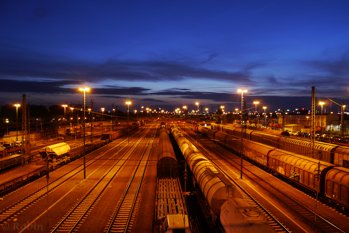 Bei einer Fahrradtour entstand durch Zufall dieses Bild von der Einfahrgruppe im  Rangierbahnhof Mannheim. Die orangenen Farben der beleuchteten Gleise passen wie ich finde sehr gut zum blauen Nachthimmel.